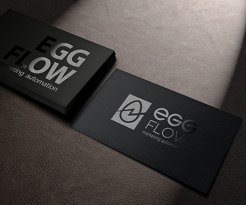 EggFlow business cards in silver foil on a leather surface