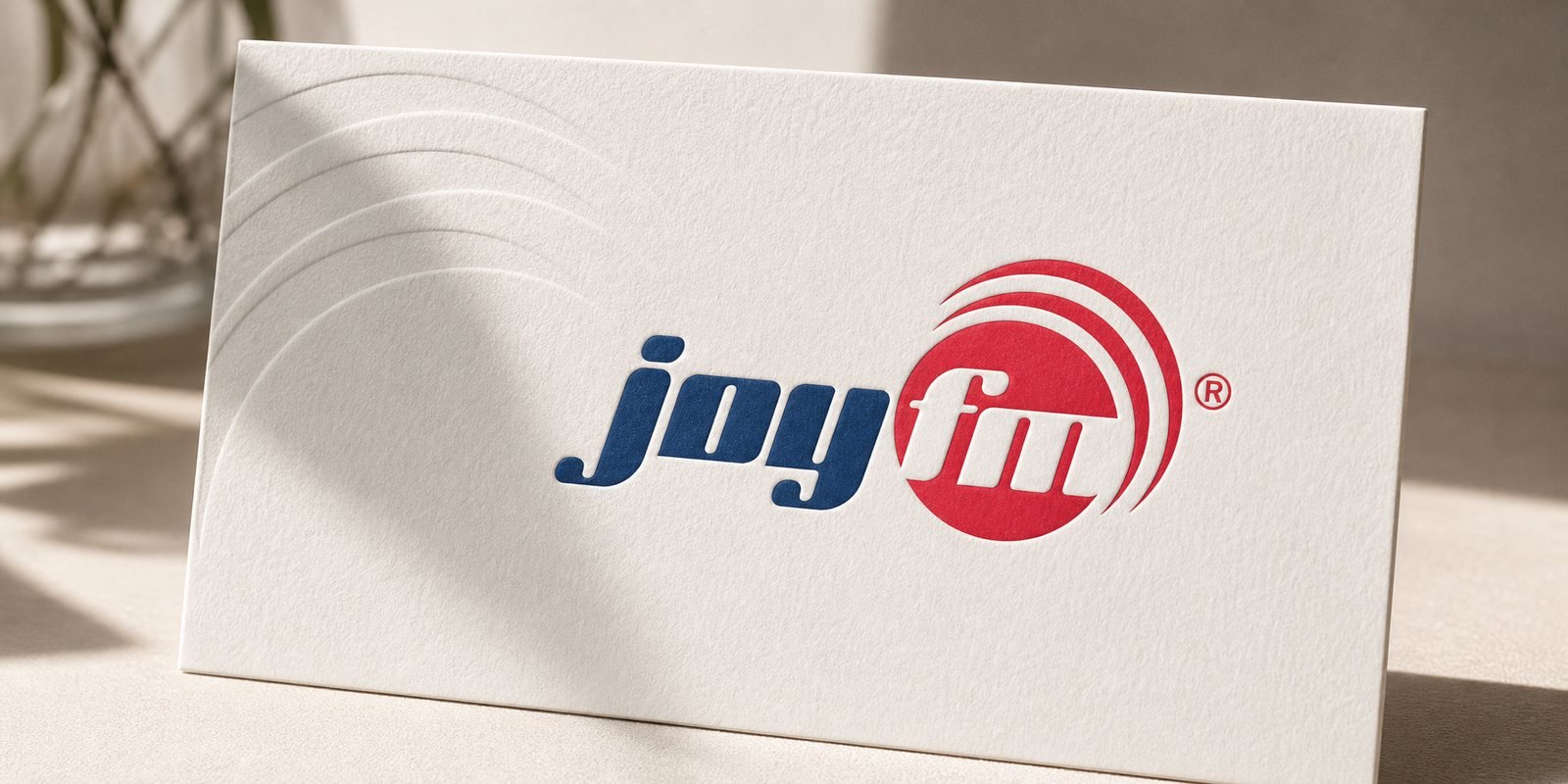 Dấu hiệu JoyFM cỡ lớn: chữ joy navy bên vòng tròn đỏ ôm chữ fm và các vòng sóng phát thanh