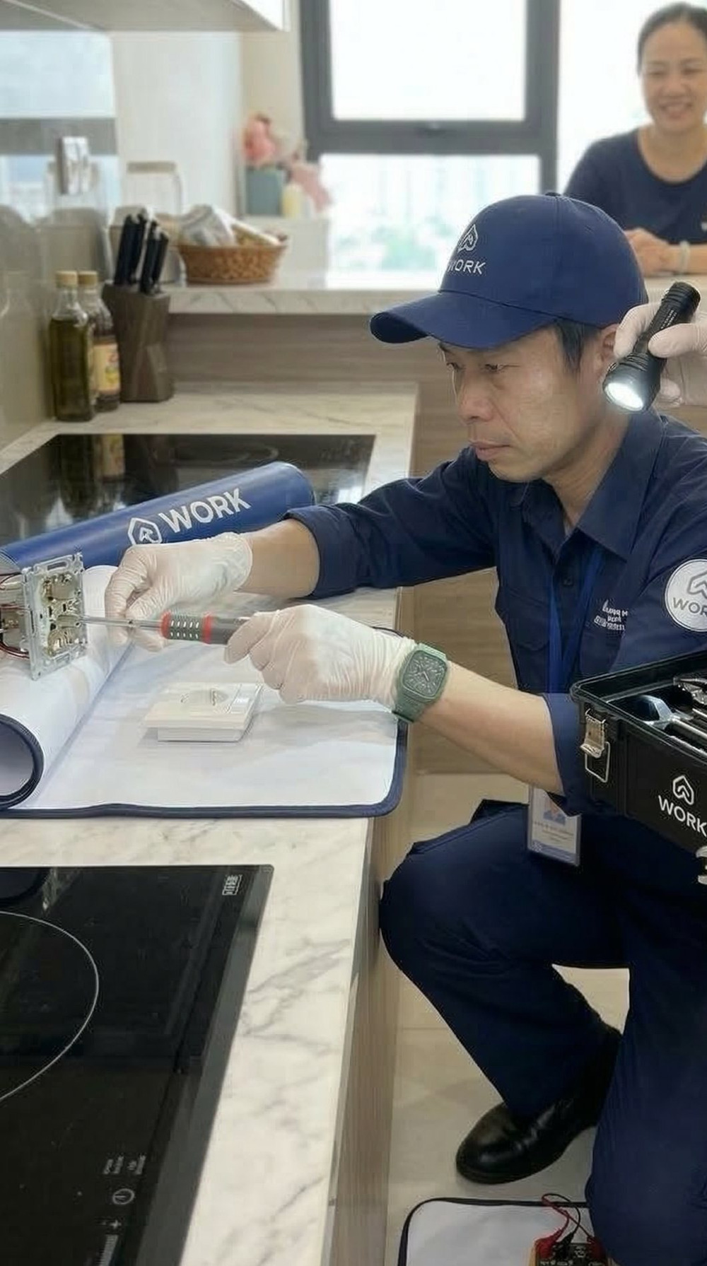 Kỹ thuật viên kythuat.work kiểm tra bếp từ trên mặt bàn đá của căn hộ