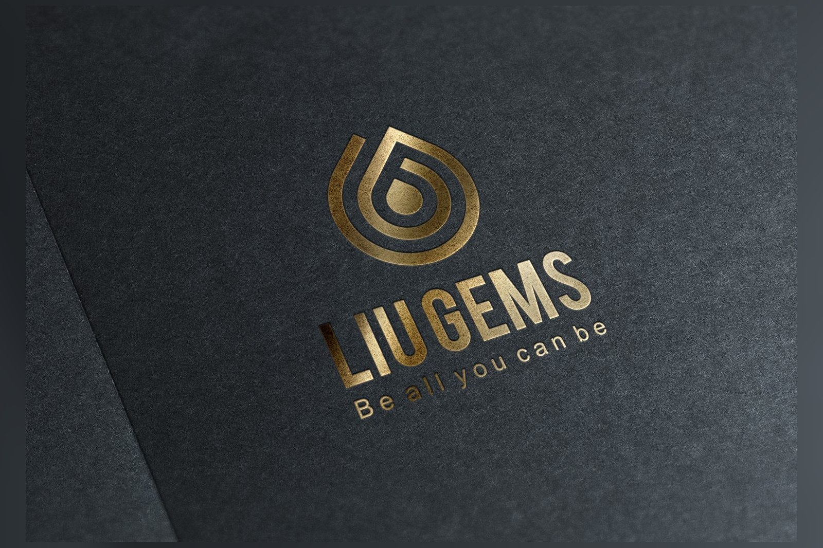 The LiuGems logo gold-foiled on black art paper, the spiral droplet mark and wordmark catching raking light