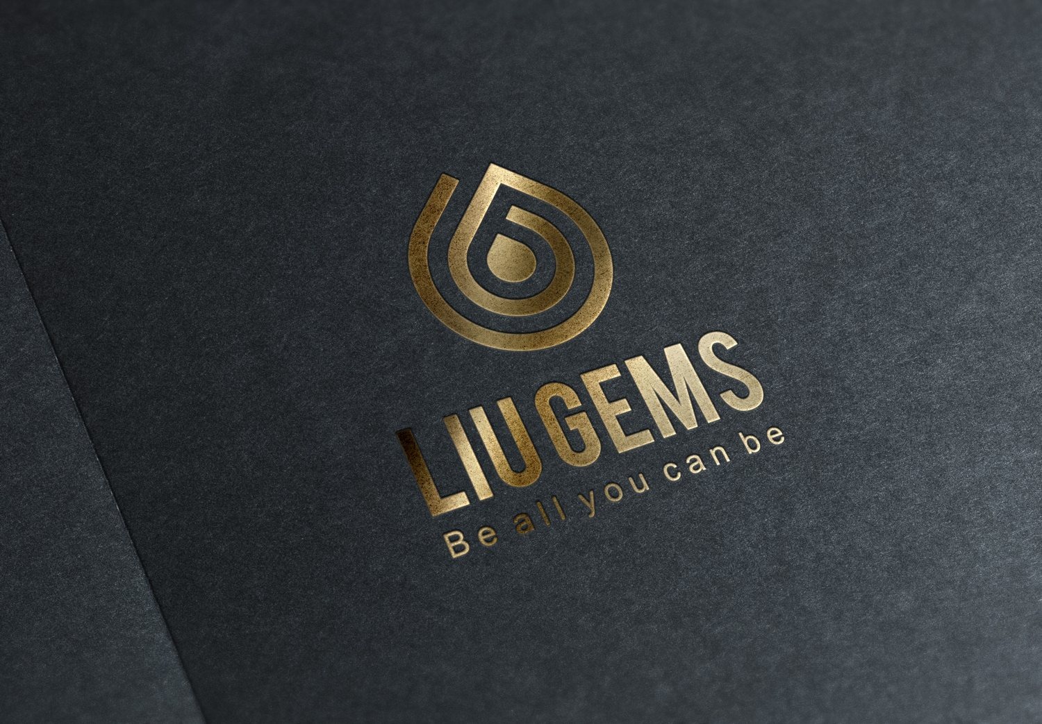 Logo LiuGems ép nhũ vàng trên giấy mỹ thuật đen, mark giọt nước xoắn và chữ LiuGems nổi lên dưới ánh sáng nghiêng