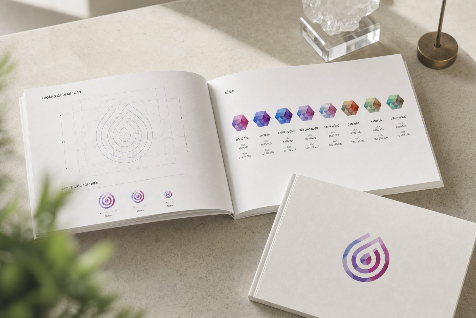 The LiuGems brand guideline open on a stone table, the left page showing clear-space rules on the seven-circle grid and the right page the eight colourways with names and print references