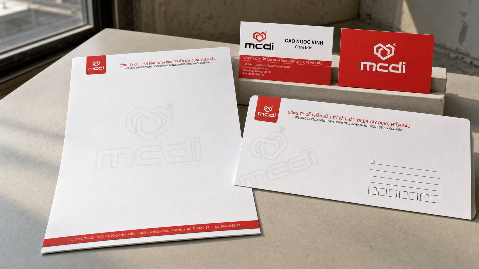 mcdi letterhead, envelope and business cards laid on a concrete surface