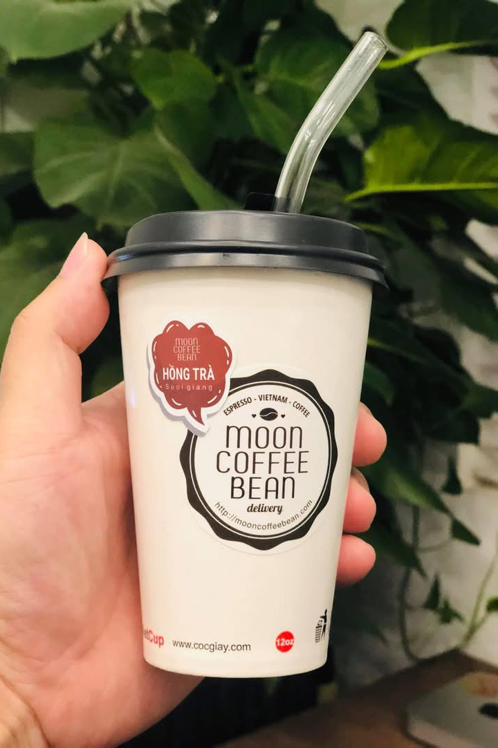 Black tea flavour tag · A deep red bubble naming the drink and its origin A Moon Coffee Bean cup wearing the deep red Suối Giàng black tea tag